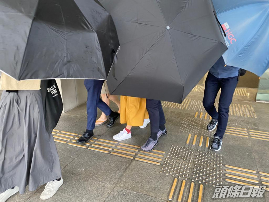 被告(左二)在傘陣掩護下離開法院。張旭珊攝