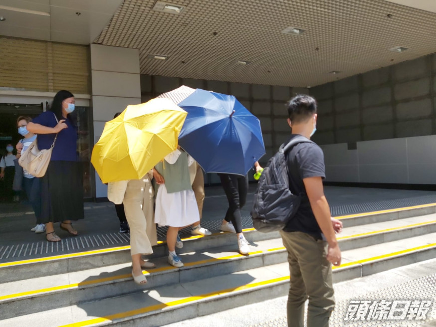 被告劉曉敏在傘陣下離開(綠白色衫)。羅綽堯攝