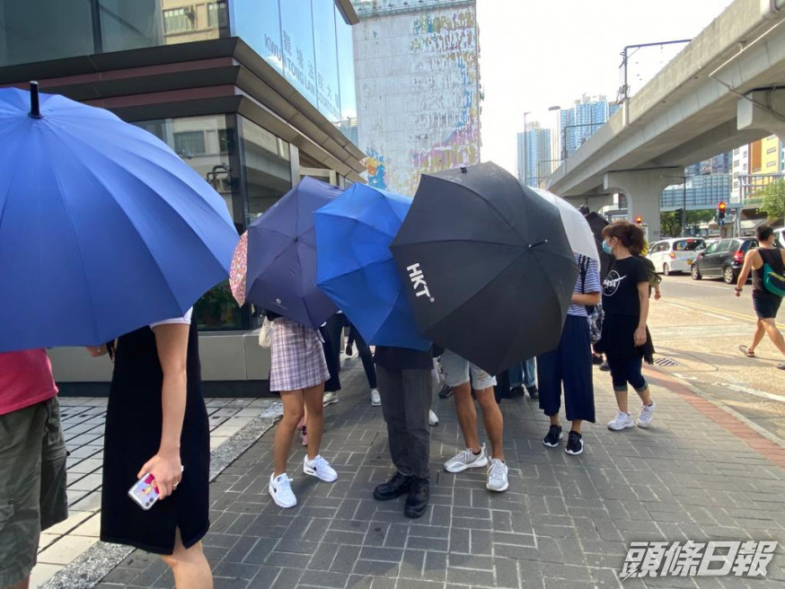 被告在傘陣掩護下離開法院。 張旭珊攝
