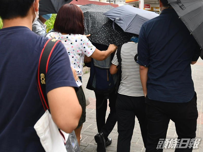 吳智晉在多人掩護下離開法院。