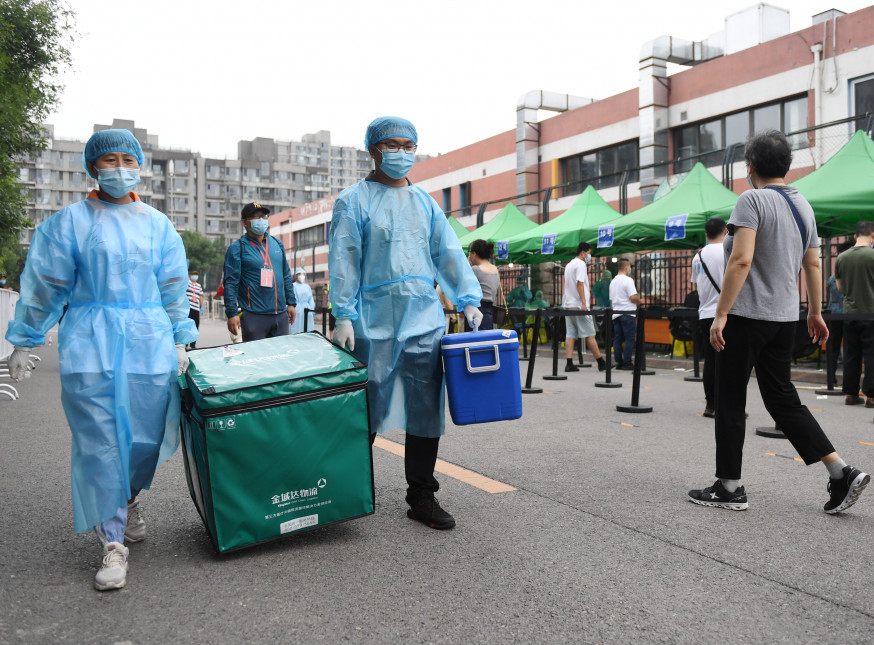 北京再現本土個案。北京金域醫學檢驗實驗室的工作人員從朝陽區一處檢測點將採集到的檢測樣本送回實驗室。新華社圖