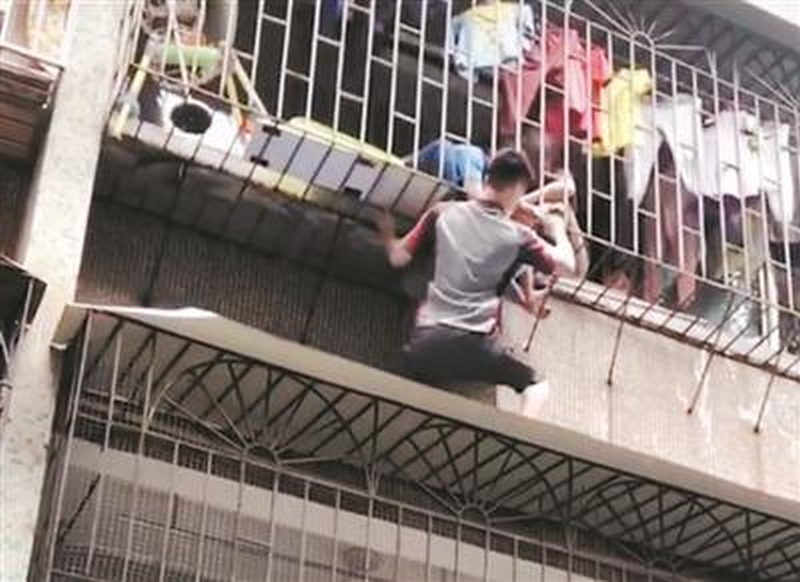 廣州番禺市橋一名男童頭卡3樓防盜網,快遞員徒手爬樓托舉救人。(網圖)