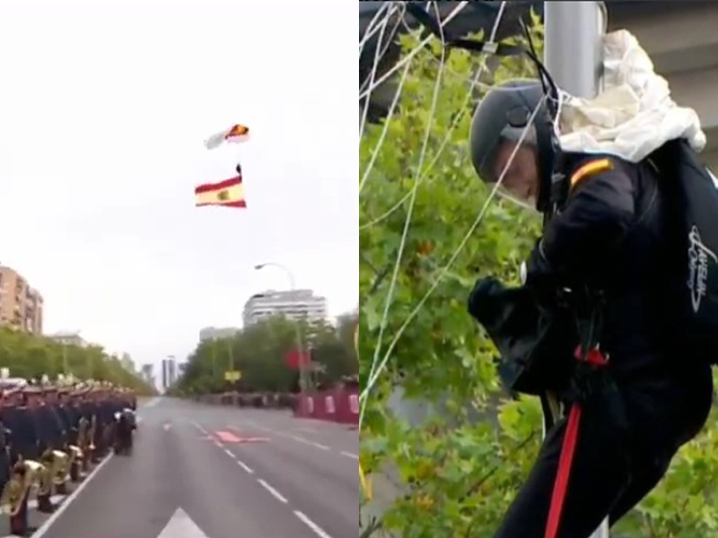 西班牙國慶閱兵上,傘兵攜帶國旗從天而降,向前來觀禮的國王致敬,惟撞上一旁路燈並掛在上面。(網圖)