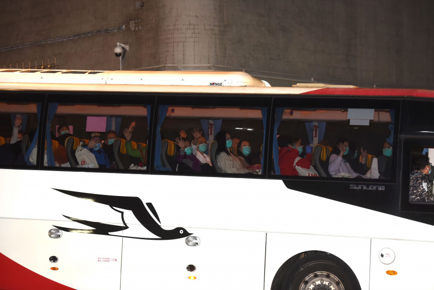 首批湖北返港人士完成隔離令,今晨乘旅巴離開駿洋邨,向車外人揮手。尹敬堂攝