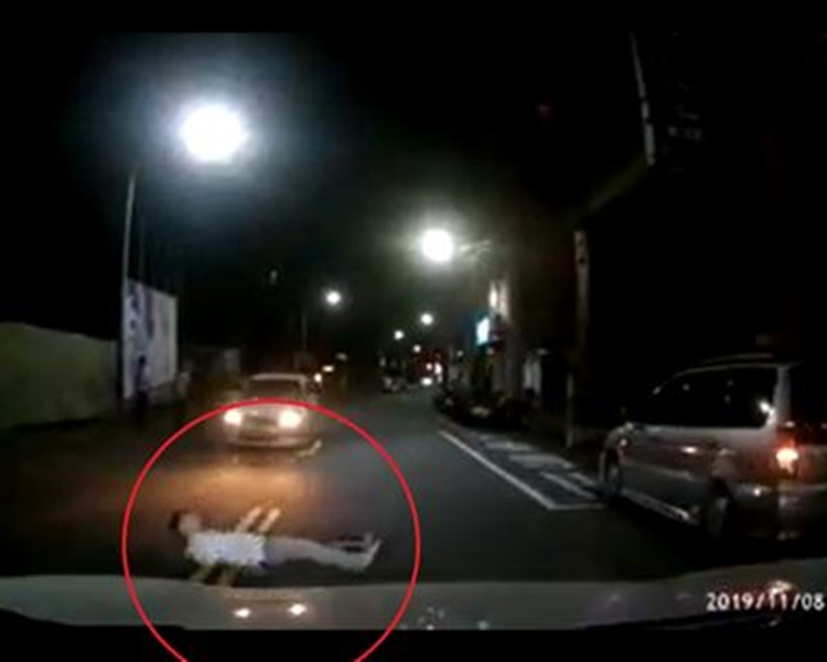 男子突然在汽車駛近時衝出馬路躺地。網圖