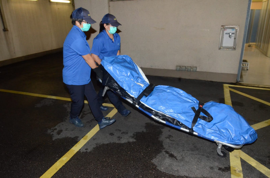 死者遺體由仵工舁送殮房。